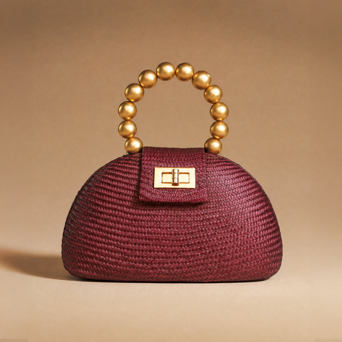 The Orla in maroon buntal straw styled against a warm backdrop