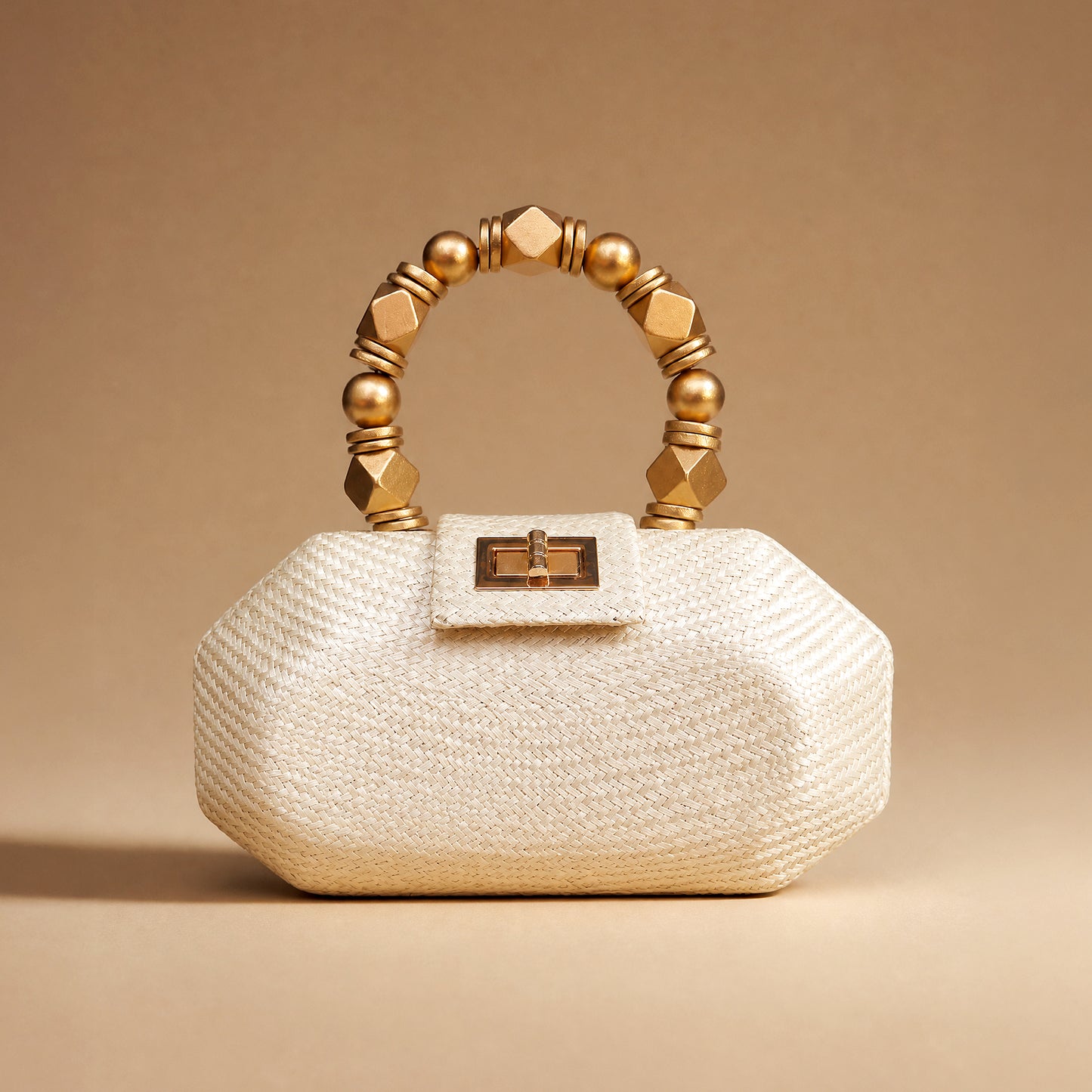 The Melia ivory woven straw bridal clutch styled against a warm backdrop