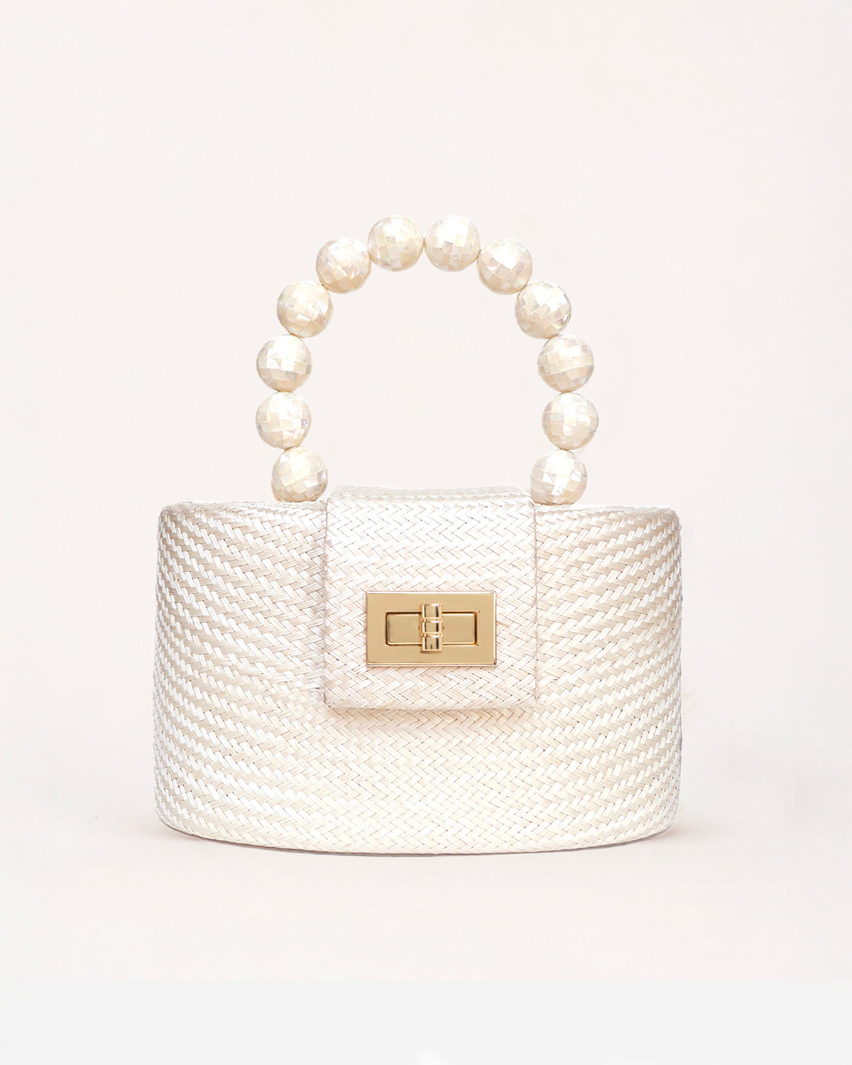 A small structured handbag with a textured cream woven body, a top handle made of mother of pearl beads, and a gold-tone clasp on the front flap, photographed against a clean off-white background.