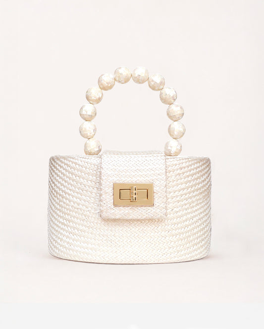 A small structured handbag with a textured cream woven body, a top handle made of mother of pearl beads, and a gold-tone clasp on the front flap, photographed against a clean off-white background.