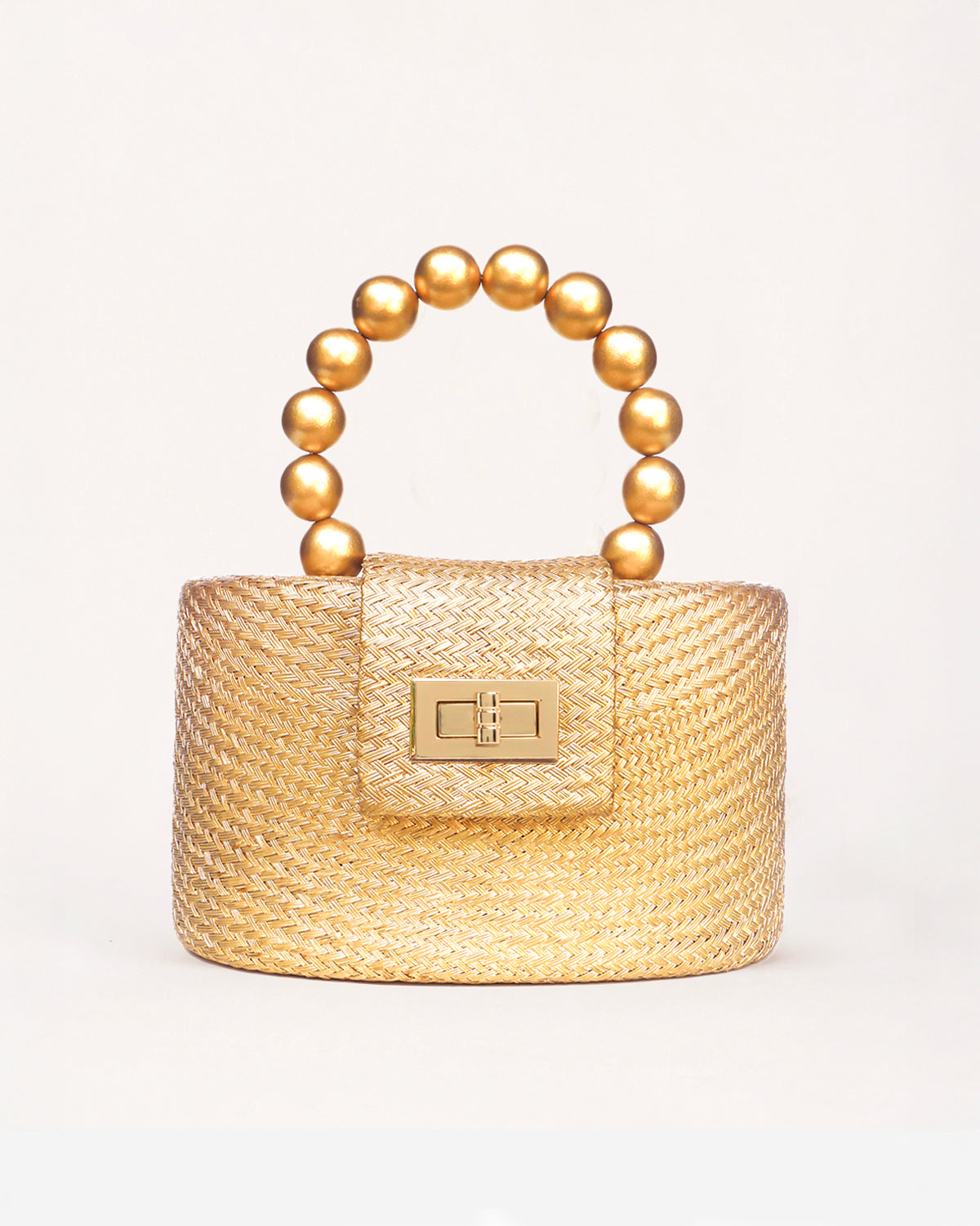 A small round structured woven handbag in warm gold-toned material with a curved top handle made of metallic gold beads and a rectangular gold-tone front clasp, shown on a clean white background.