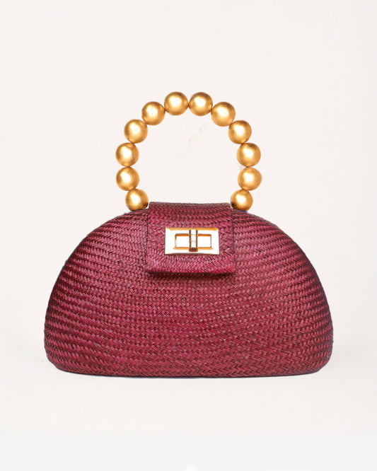 The Orla maroon woven straw half-moon bag with gold beaded handle, front view
