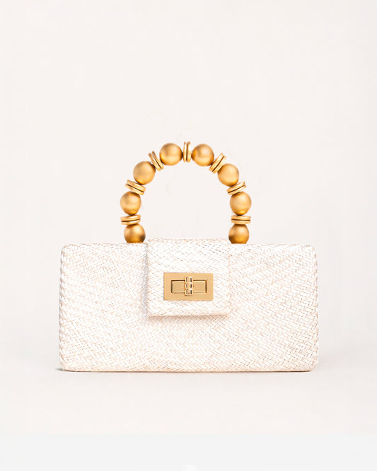 A structured cream-colored woven handbag with a gold-tone clasp and a unique arched top handle made of gold-toned beads, set against a plain off-white background.